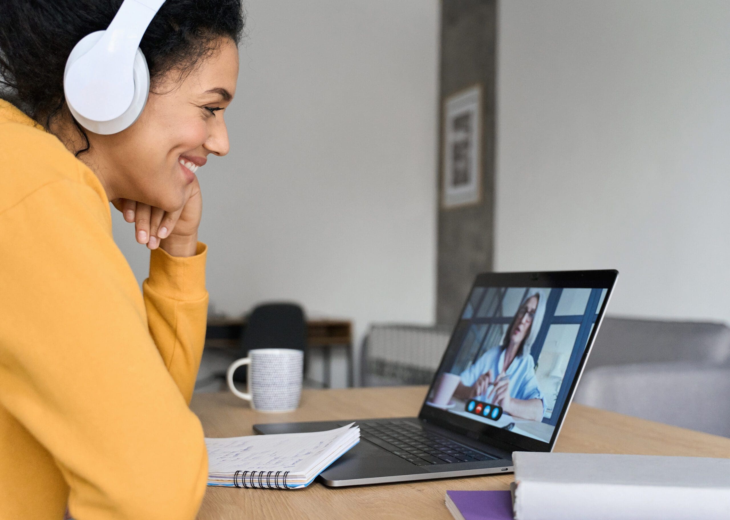 Woman in headphones on video call, taking notes.