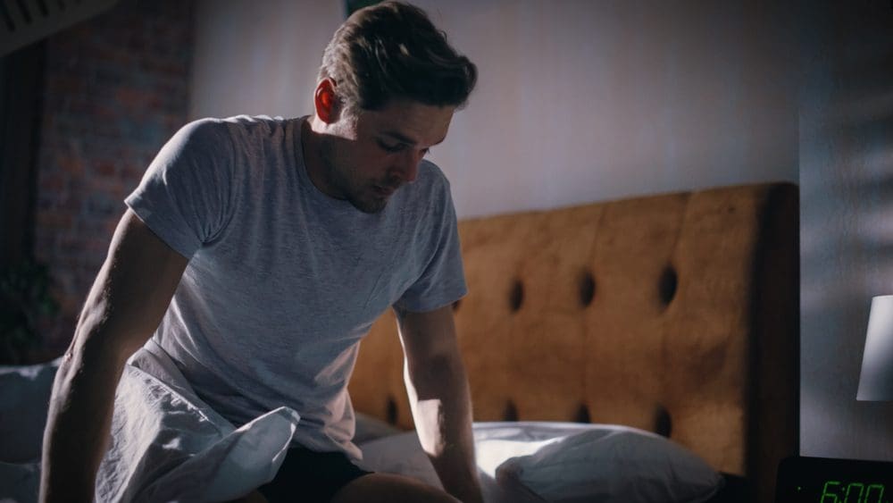 Man waking up at 6AM in bedroom.