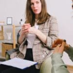 Business woman sat with clipboard on lap discussing Occupational Health