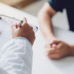 doctor holding test results and consulting patient at desk medic