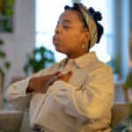 mindful break at home of black woman practicing calming deep breathing exercise for stress relieve.